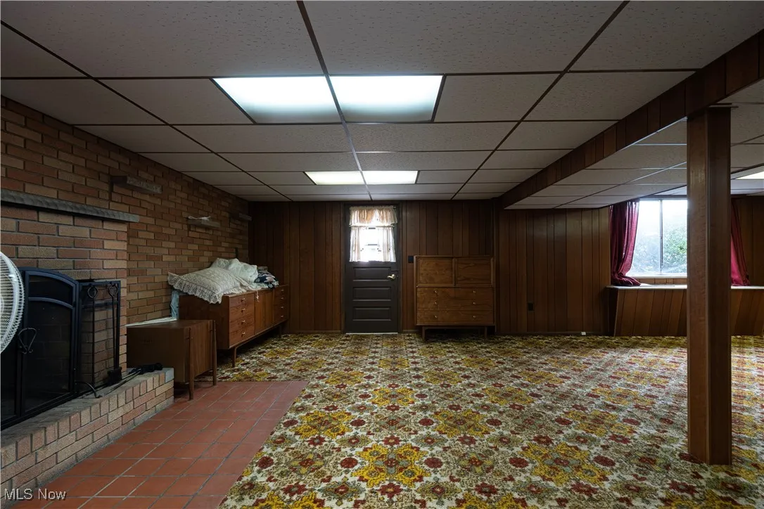Below grade area with a drop ceiling and a brick fireplace
