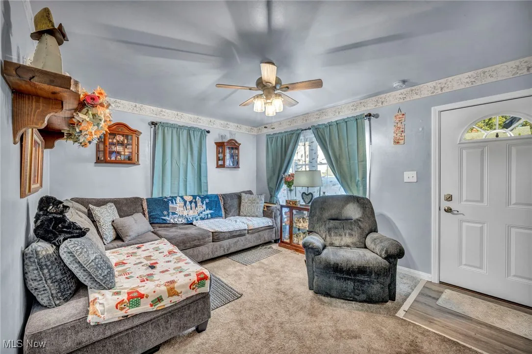 Carpeted living area with baseboards and ceiling fan