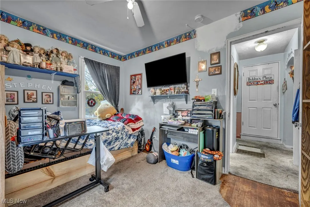 Bedroom with carpet floors, ceiling fan, and wood finished floors