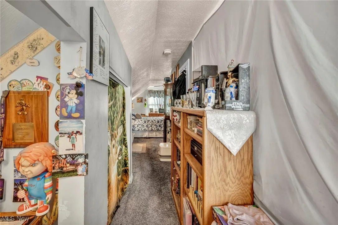 Corridor featuring dark colored carpet and a textured ceiling