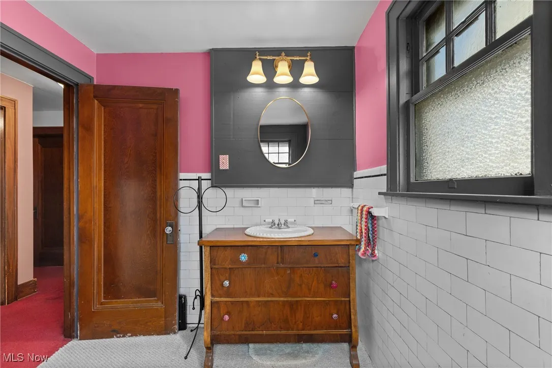 Bathroom featuring tile walls, vanity, and a wainscoted wall