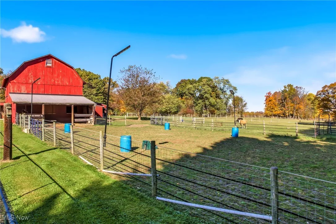 Fenced paddocks extend from the striking red barn, offering secure and well-maintained areas for horses or other animals. The open layout allows for easy movement and excellent visibility, Hosting: 1 dry lot/Arena 60x100, a turnout, 2 additional pastures, a dog park, and carport for trailer/rv storage