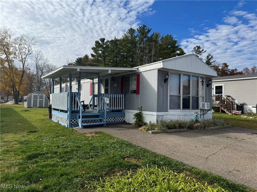 Manufactured / mobile home with a storage shed, a front lawn, and a porch