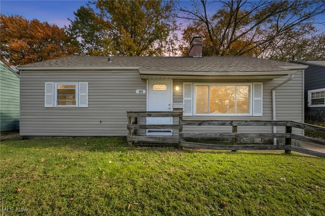 View of front of home featuring a chimney, a front lawn, and a shingled roof