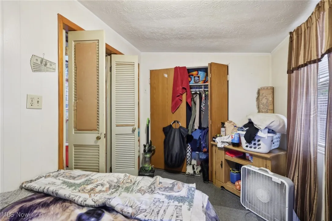 Carpeted bedroom with a closet and a textured ceiling