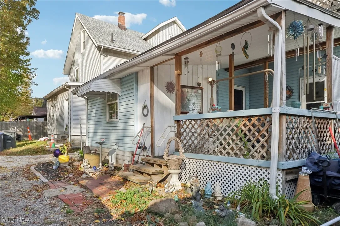 View of home's exterior featuring a chimney, a porch, and a shingled roof