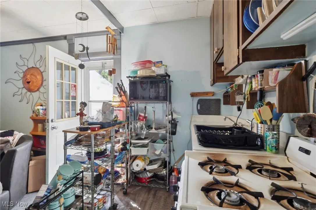 Kitchen with white range with gas stovetop and dark wood finished floors