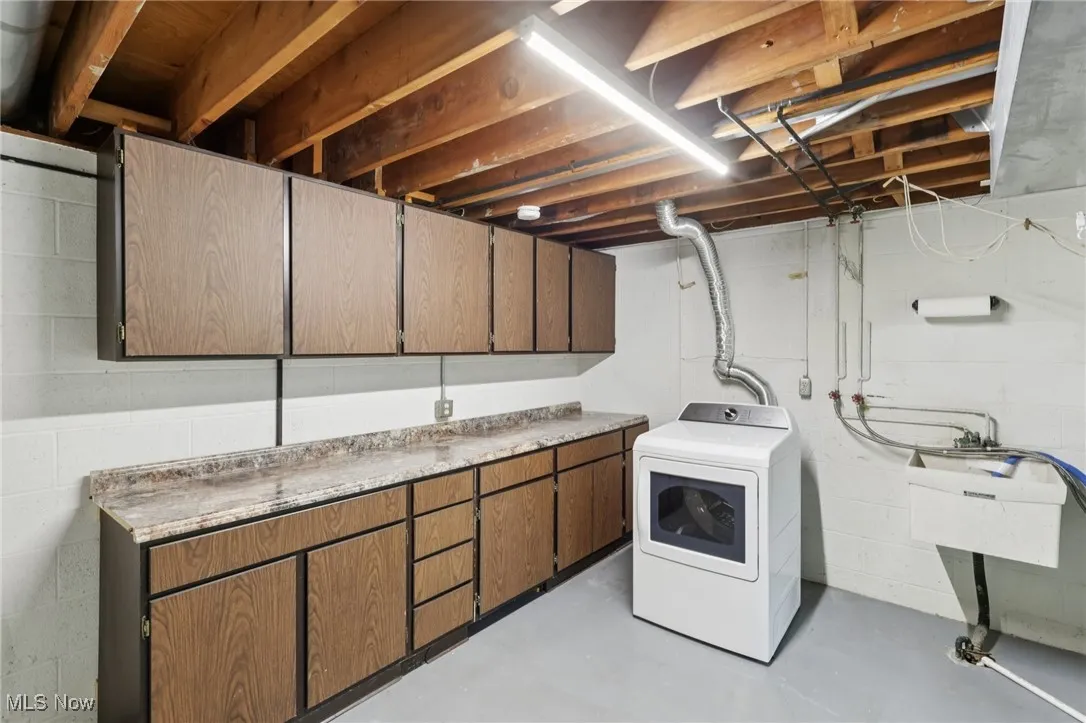 Laundry room featuring finished concrete floors, washer / clothes dryer, and cabinet space