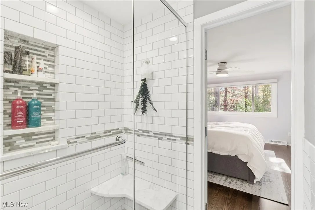 Full bath featuring wood finished floors, a walk in shower, ensuite bath, and a ceiling fan