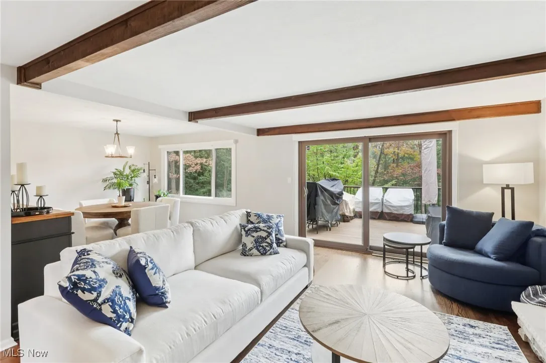 Living room featuring beamed ceiling, wood finished floors, plenty of natural light, and a chandelier