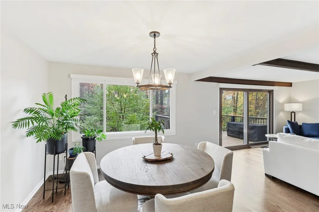Dining area featuring wood finished floors, beam ceiling, and a chandelier