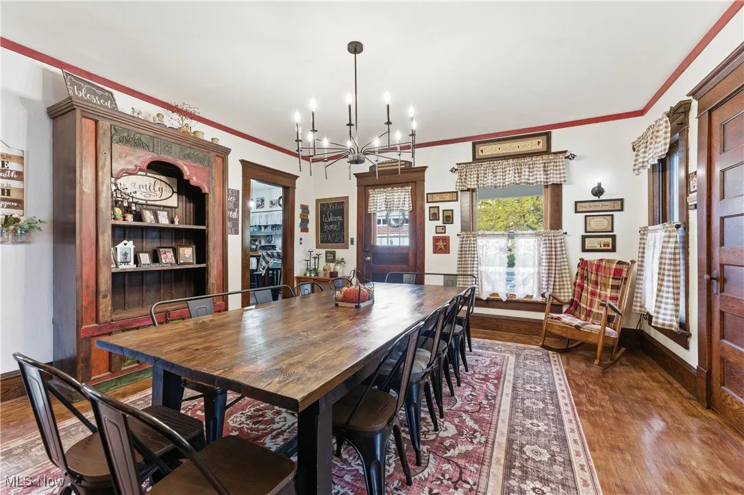 Dining area with wood flooring, ornamental molding, and a chandelier
