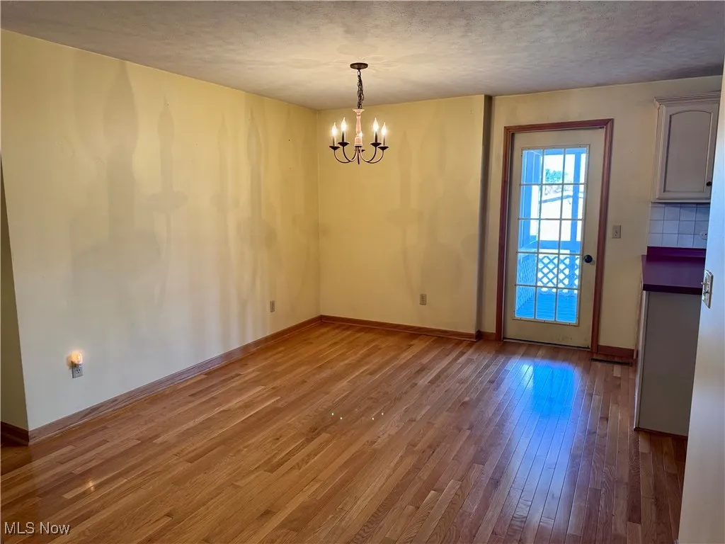 Unfurnished dining area featuring a chandelier, hardwood / wood-style flooring, and a textured ceiling