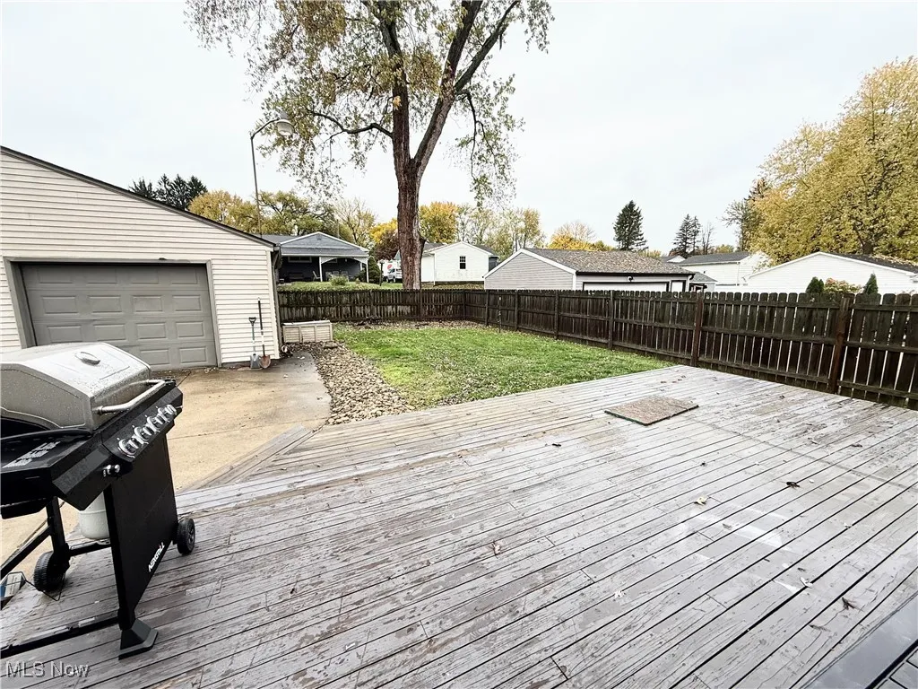 Wooden terrace featuring a fenced backyard, grilling area, a residential view, and a garage