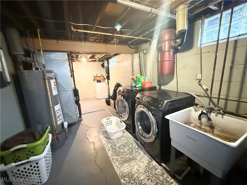 Laundry room with concrete floors, water heater, and washing machine and clothes dryer