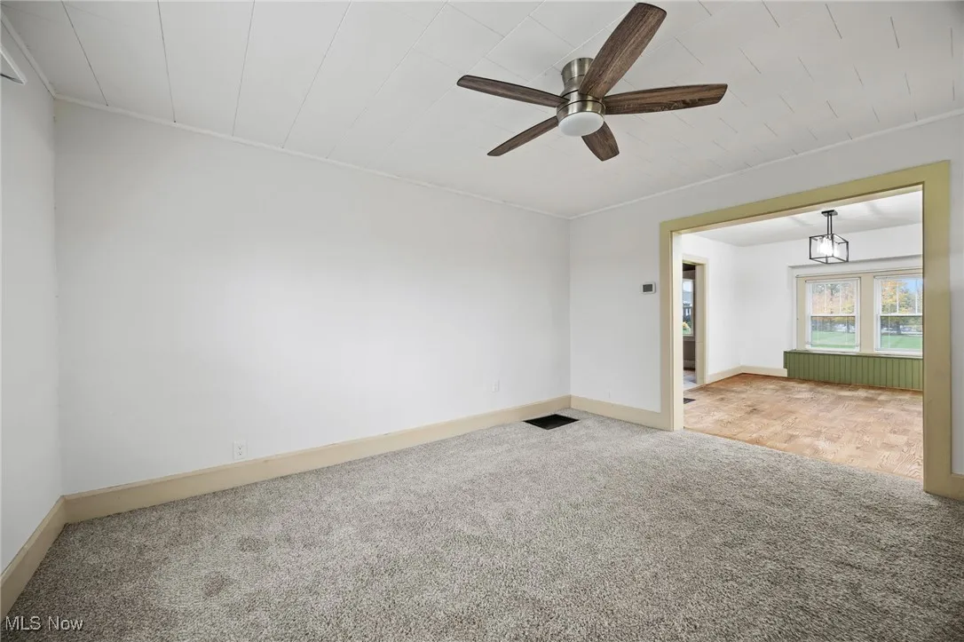 Empty room featuring carpet flooring and a ceiling fan