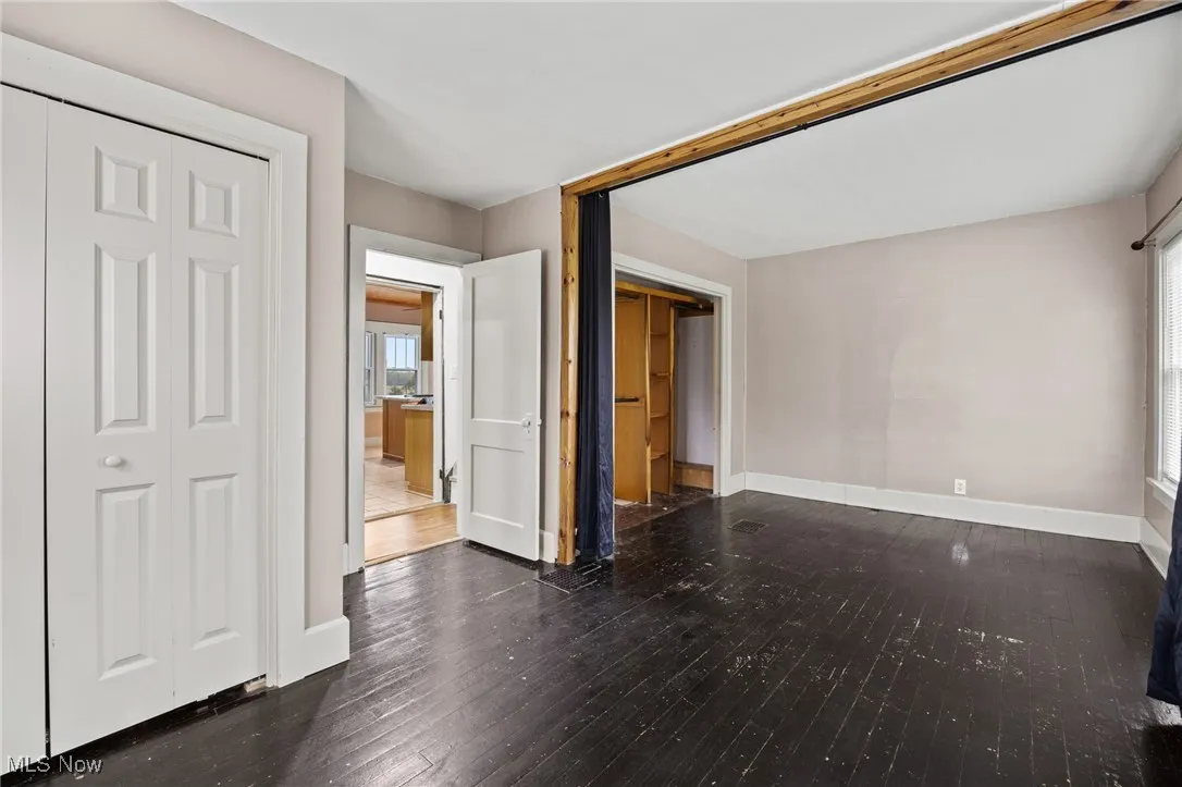 Unfurnished bedroom with dark wood finished floors, multiple windows, and a closet