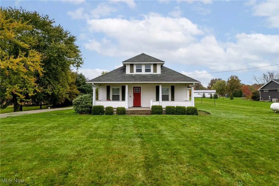 Bungalow-style house with covered porch, a front lawn, and roof with shingles