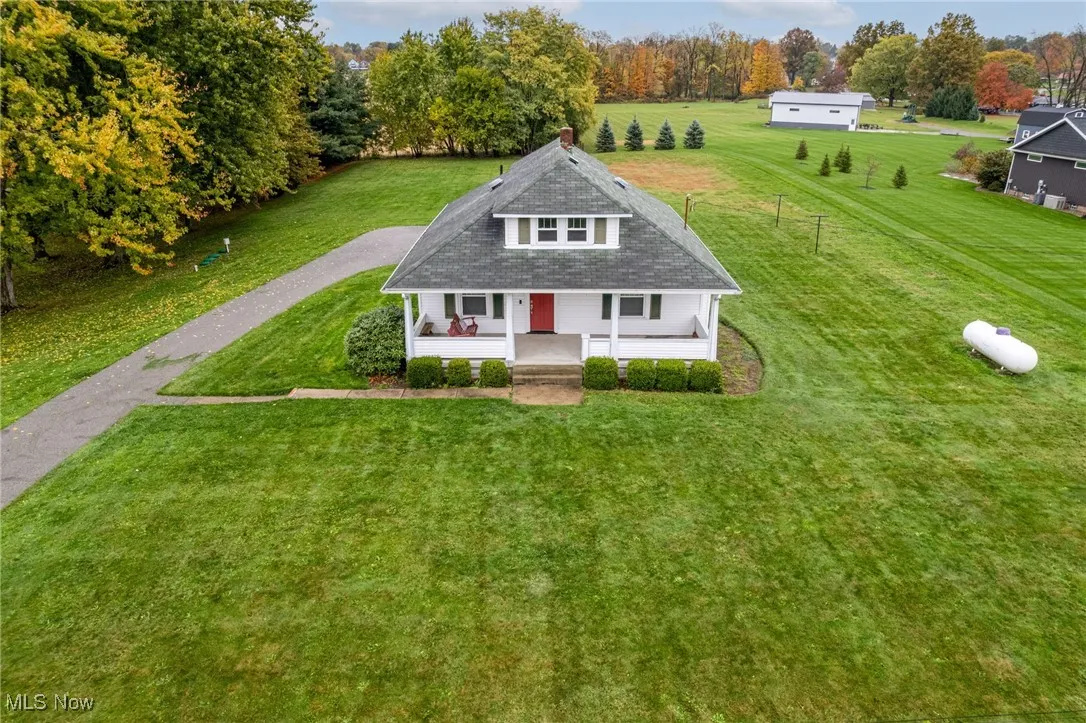 View of front of house featuring covered porch, a front lawn, driveway, and a chimney