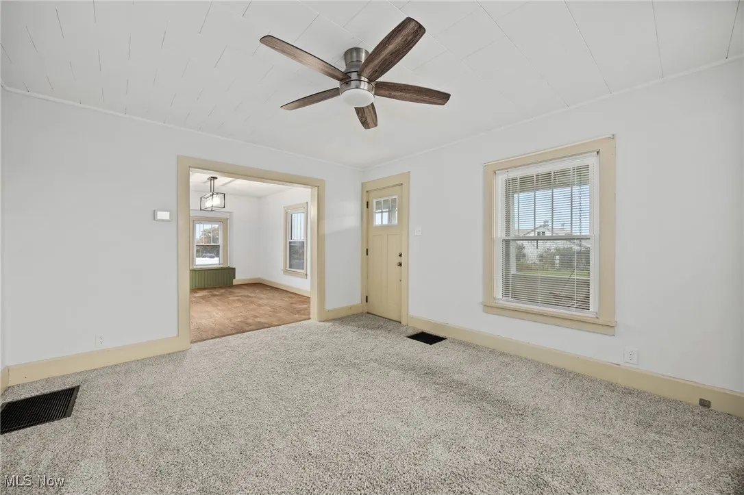Carpeted foyer entrance featuring ceiling fan and baseboards