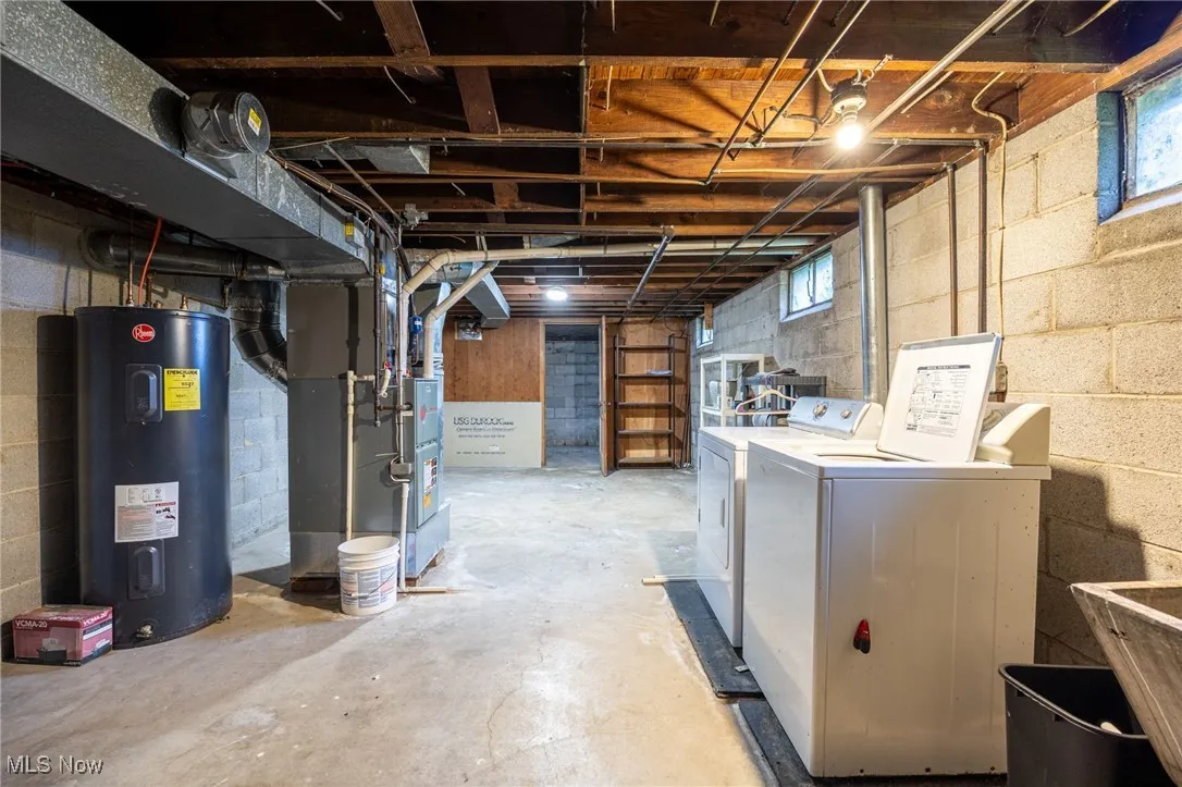Basement featuring water heater, heating unit, and washing machine and clothes dryer