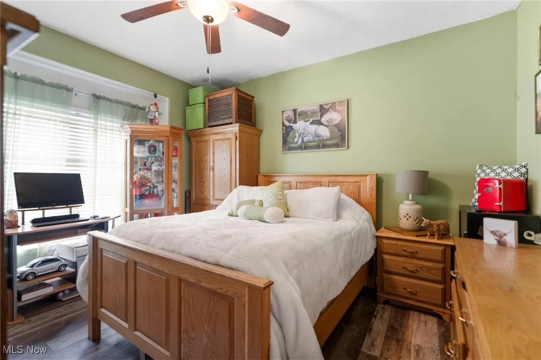 Bedroom featuring dark wood-style floors, ceiling fan, and an office area