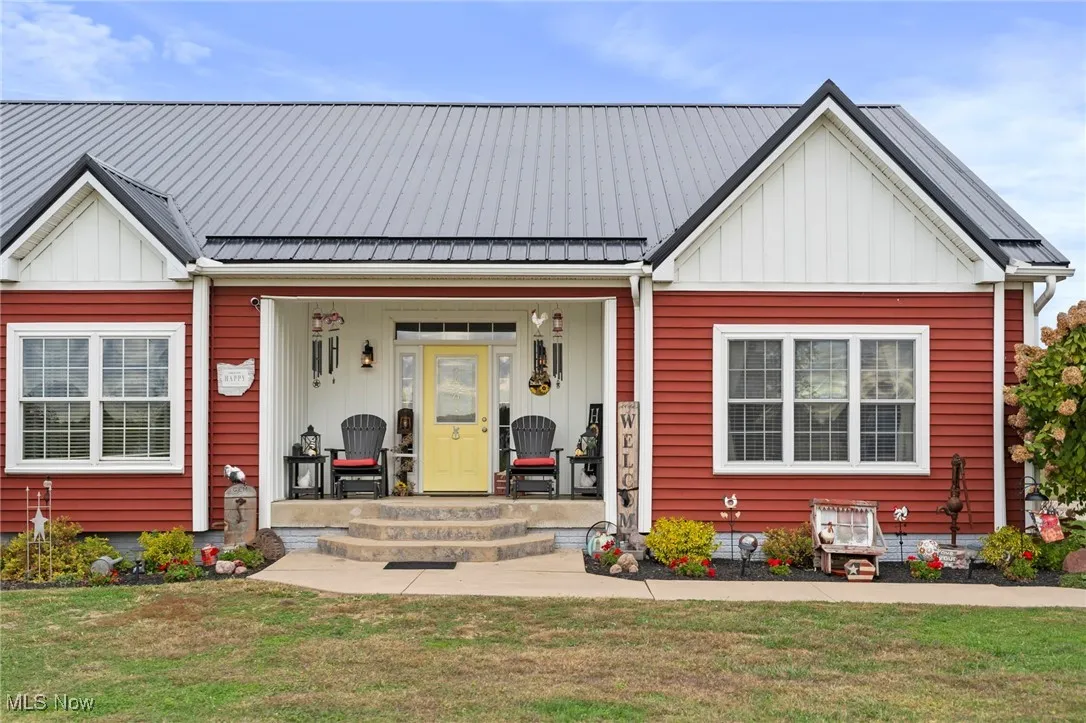 Modern inspired farmhouse with a porch, board and batten siding, a front lawn, and a metal roof