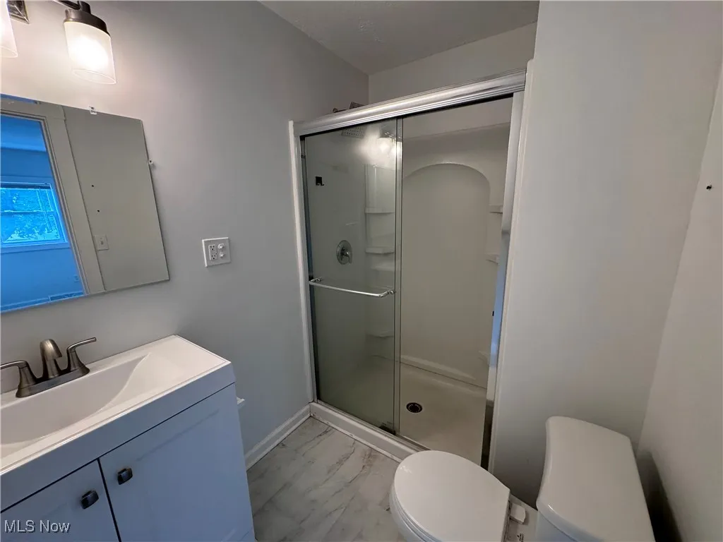 Bathroom with a shower with shower door, wood-type flooring, vanity, and toilet