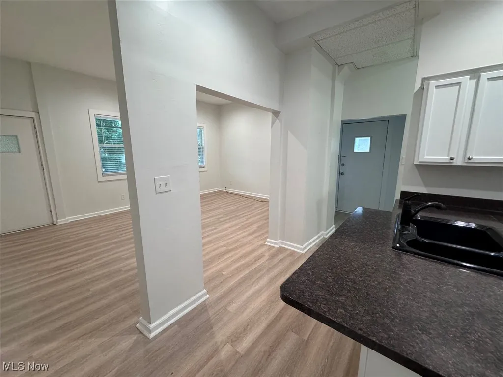 Kitchen with white cabinets, sink, a high ceiling, and light wood-type flooring