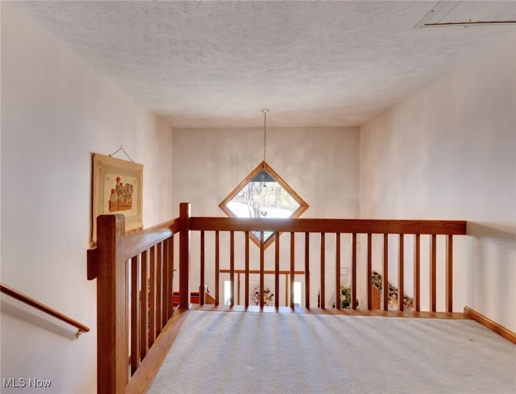 Stairs with a chandelier and a textured ceiling overlooking foyer