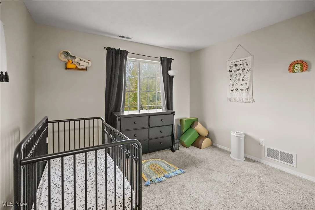 Carpeted bedroom with a nursery area and baseboards