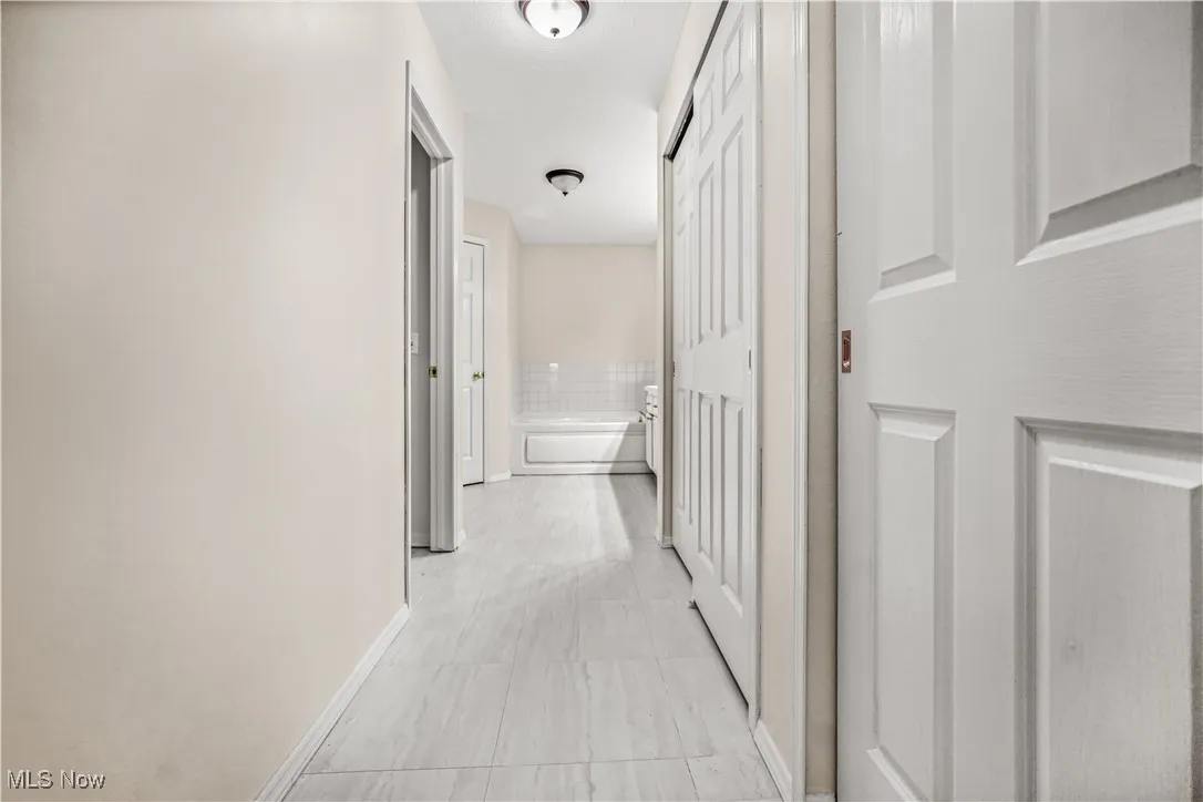 Hallway with baseboards and light tile patterned floors