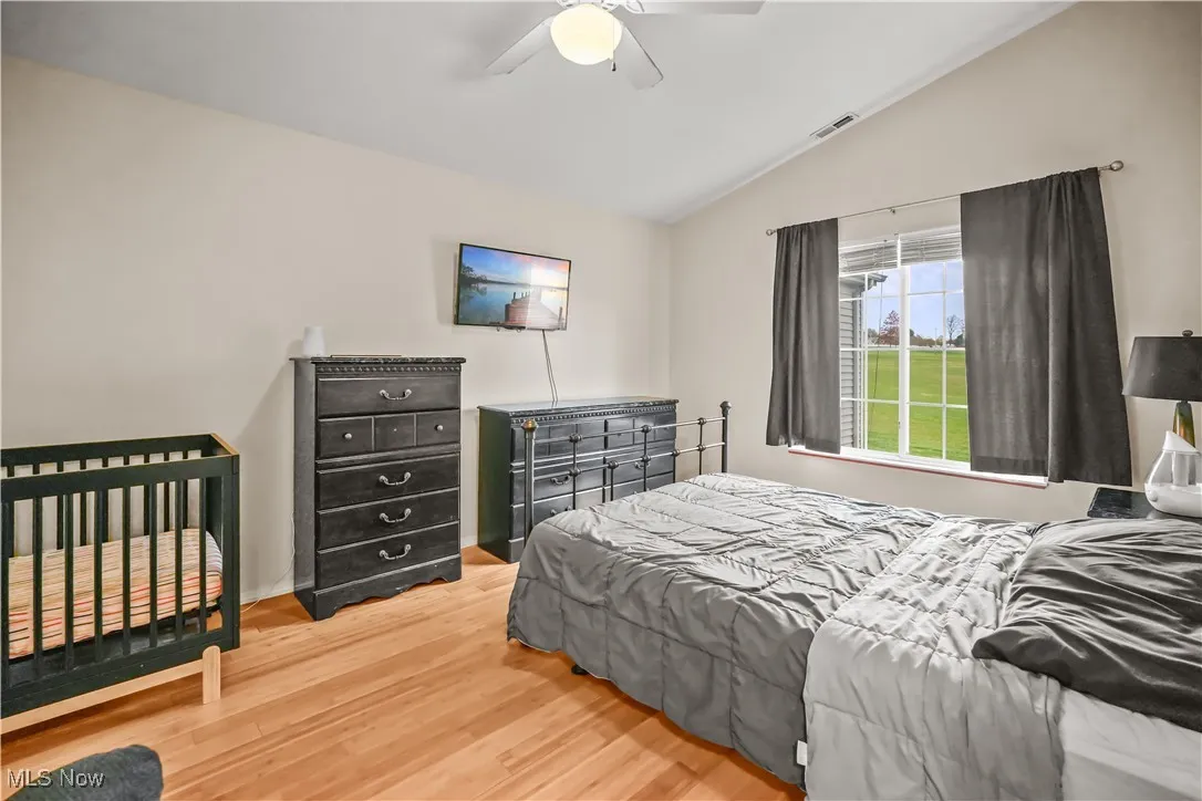 Bedroom with vaulted ceiling, wood finished floors, and ceiling fan
