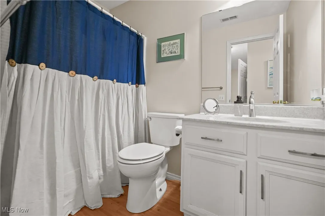 Full bath featuring a shower with shower curtain, vanity, and light wood-type flooring