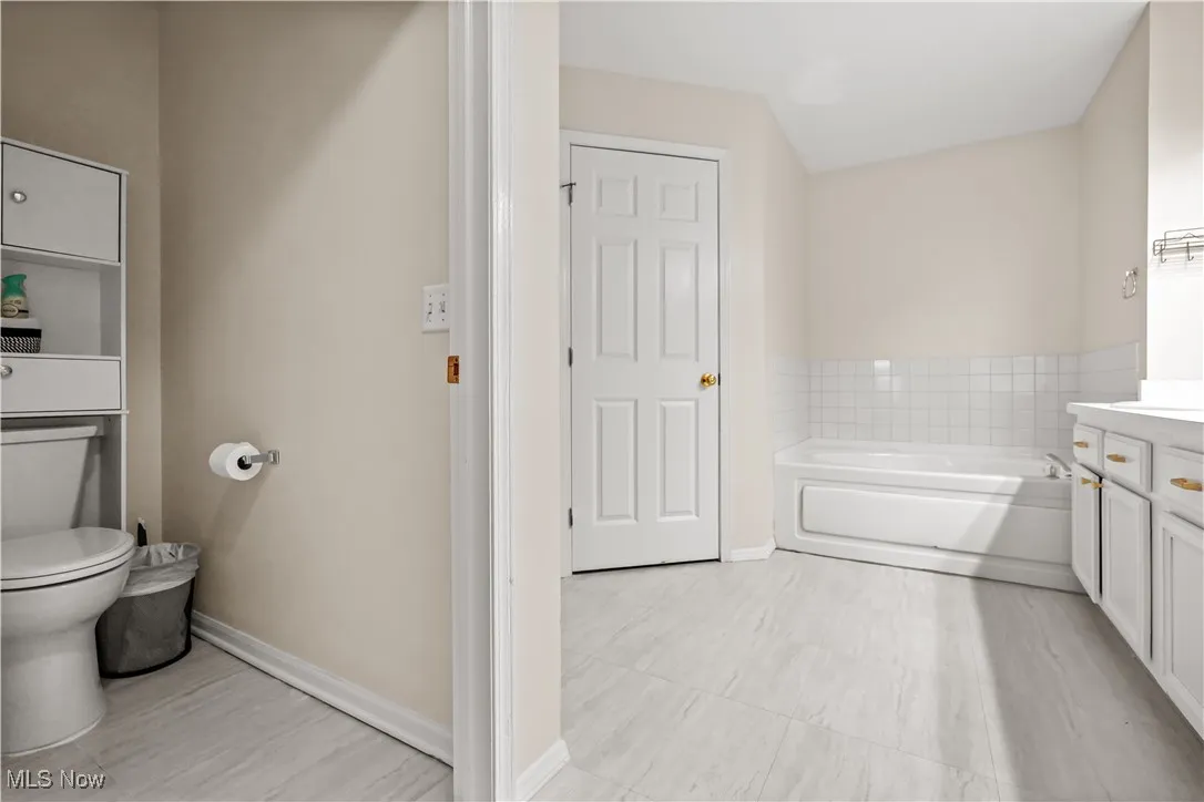 Full bath featuring vanity, a garden tub, and light tile patterned floors