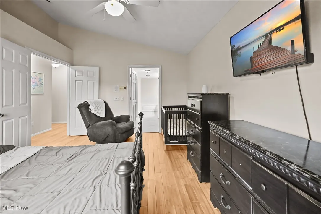 Bedroom with light wood-style flooring, lofted ceiling, and a ceiling fan