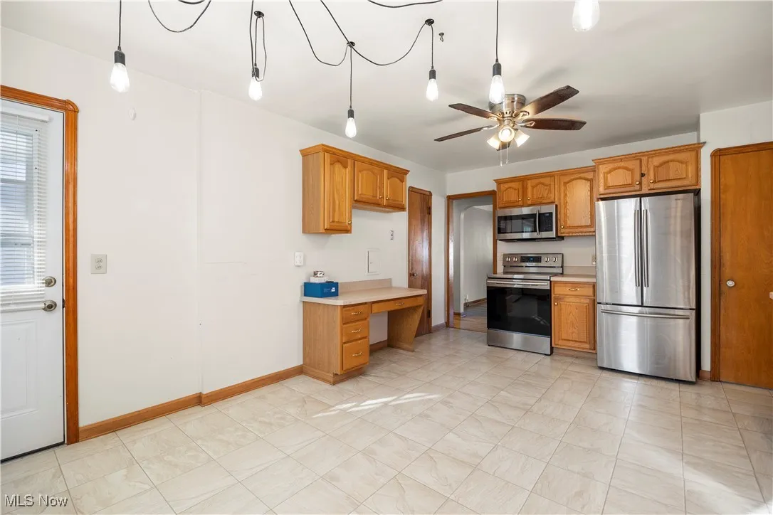 Kitchen featuring appliances with stainless steel finishes, light countertops, hanging light fixtures, and ceiling fan
