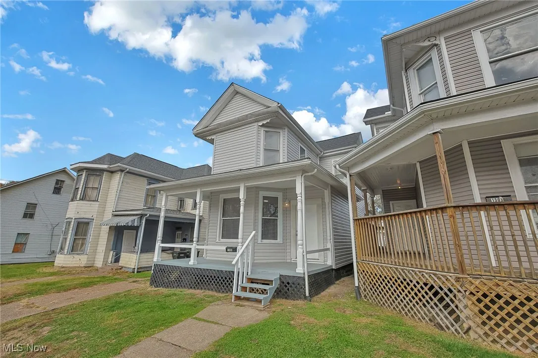View of side of property featuring covered porch and a lawn