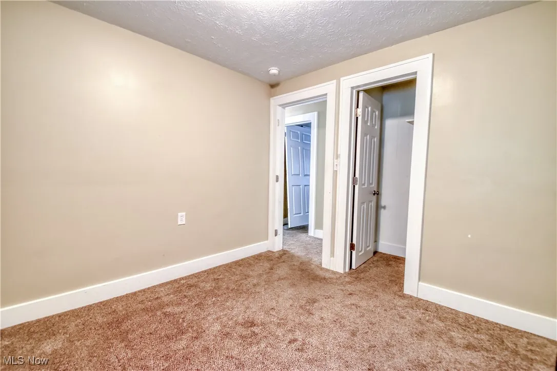 Unfurnished bedroom with carpet floors, a walk in closet, and a textured ceiling