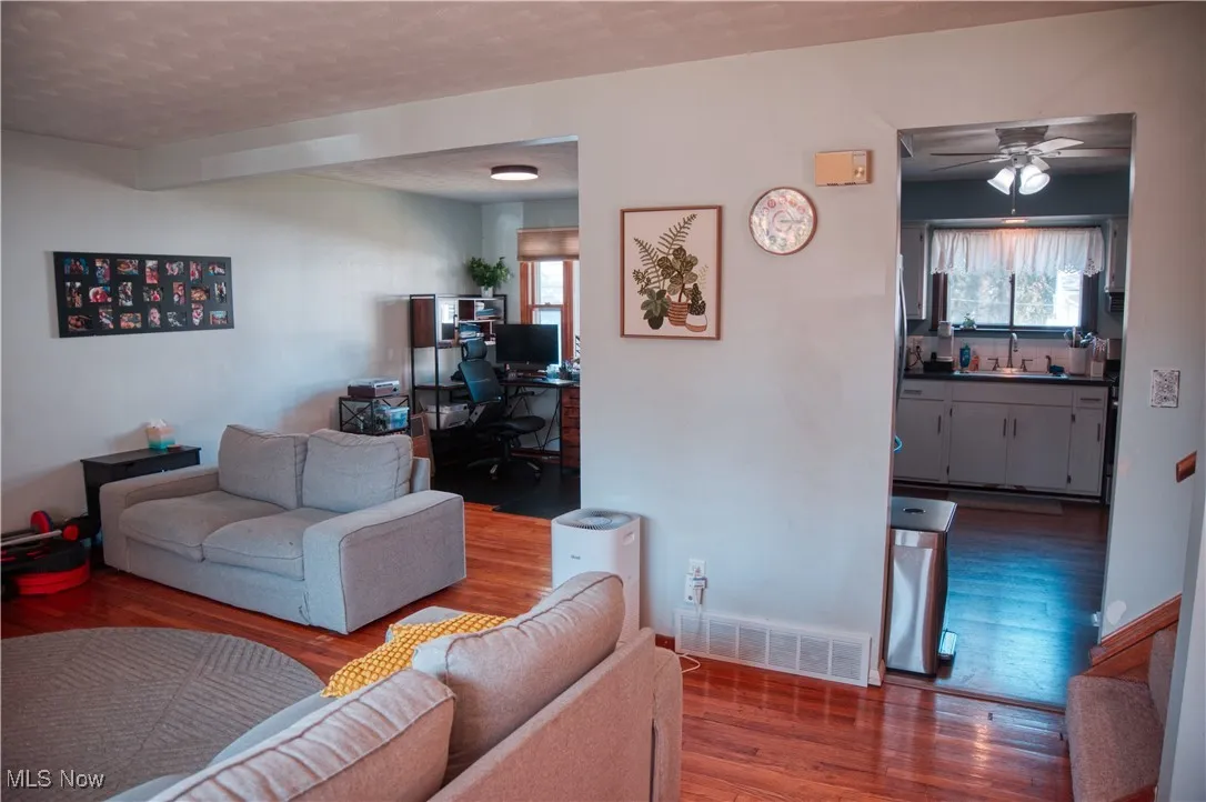 Living room with a desk, a ceiling fan, wood finished floors, and a textured ceiling