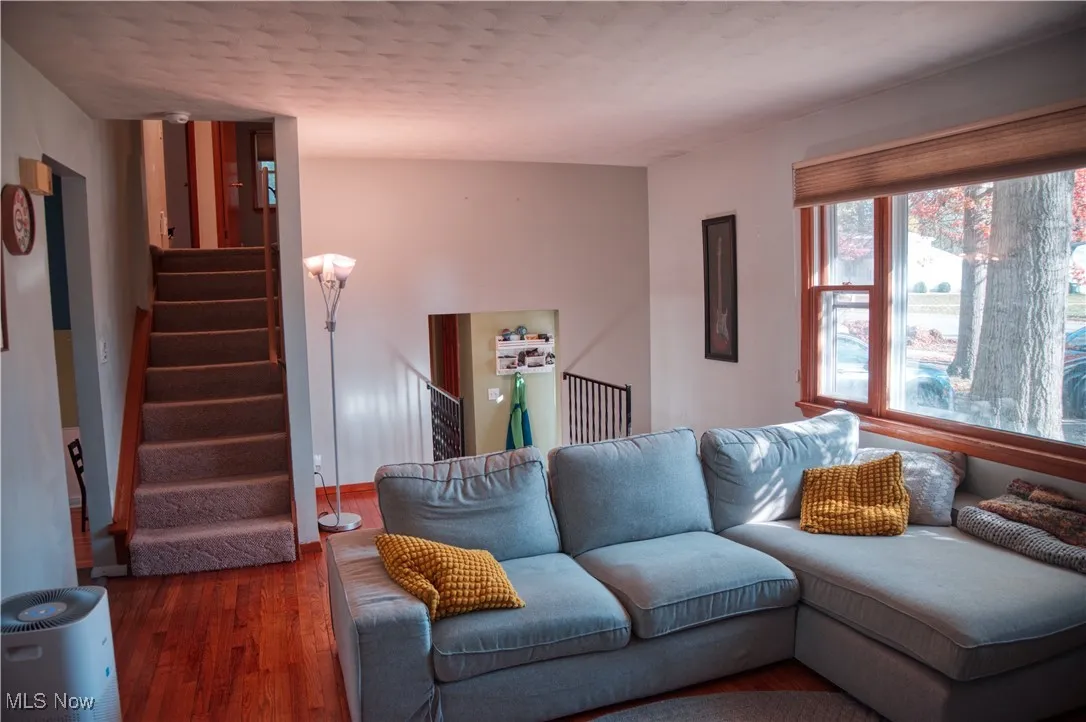 Living room with stairs, wood finished floors, and a textured ceiling