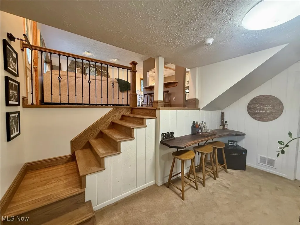 Stairs featuring a textured ceiling, wooden walls, and carpet flooring