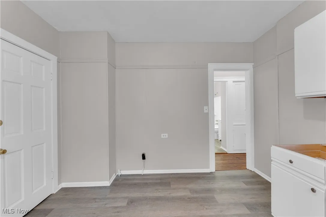Unfurnished dining area featuring light wood-type flooring and baseboards