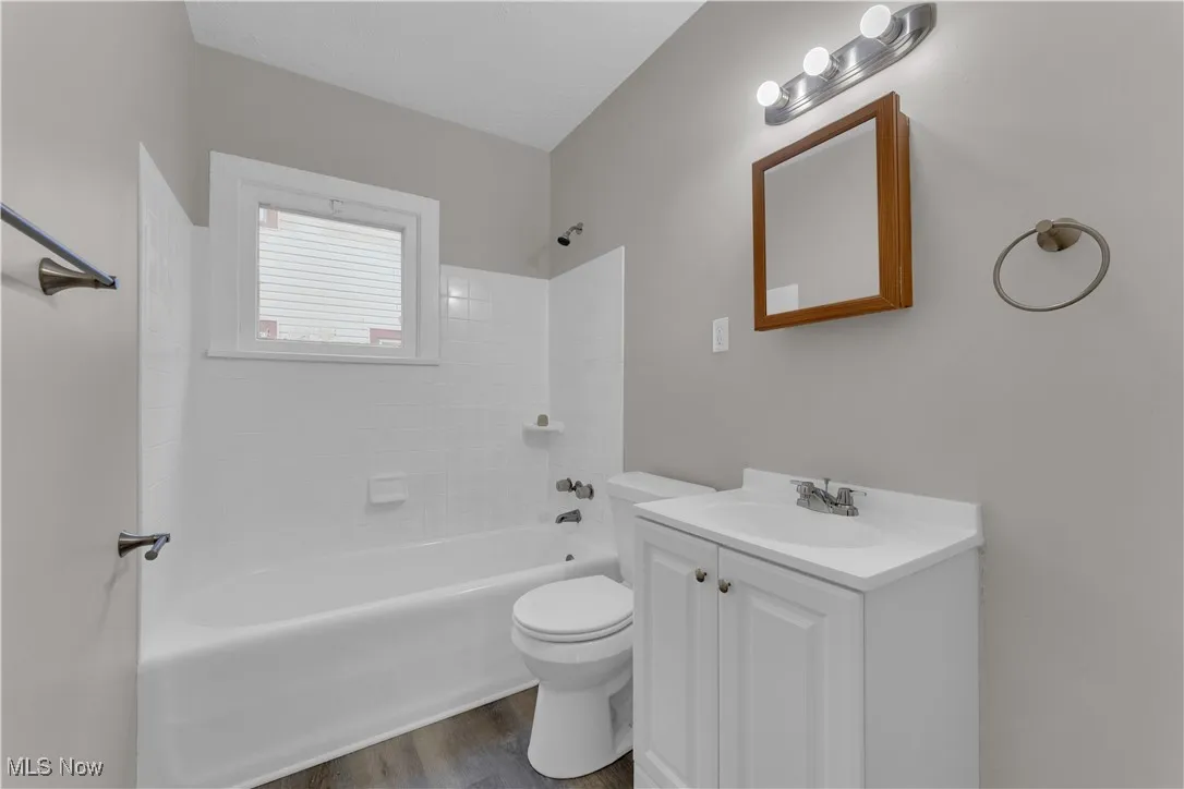 Bathroom with vanity, washtub / shower combination, and dark wood-style floors