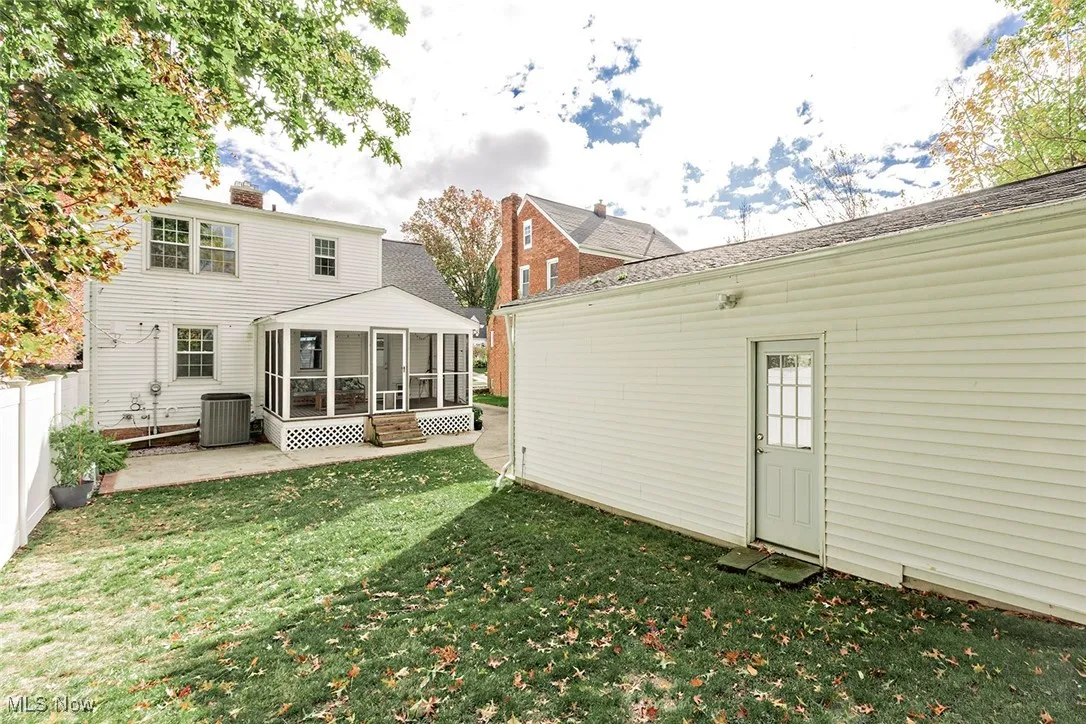 Back of property with a sunroom, a yard, and a patio area