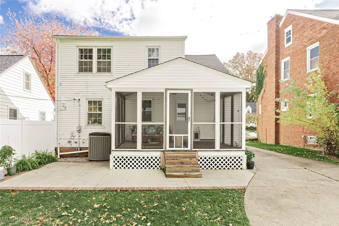 Rear view of property featuring a patio area, a sunroom, and a lawn