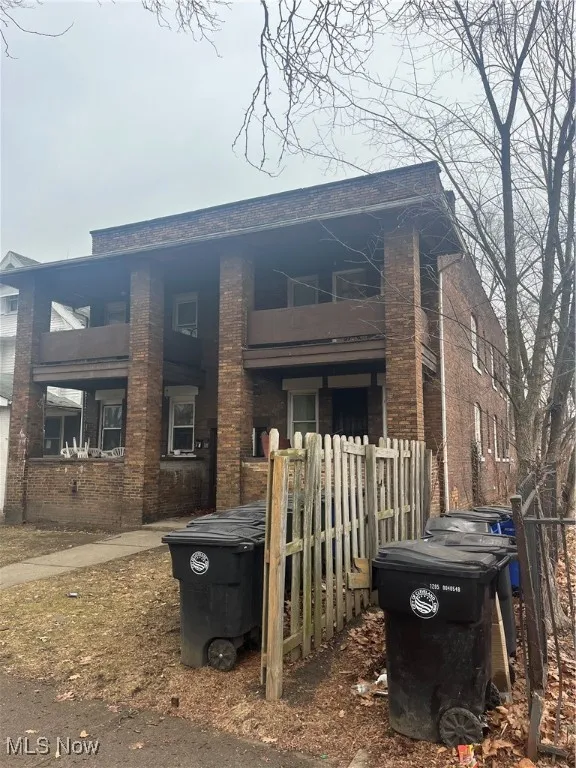 View of front of house featuring a balcony and brick siding