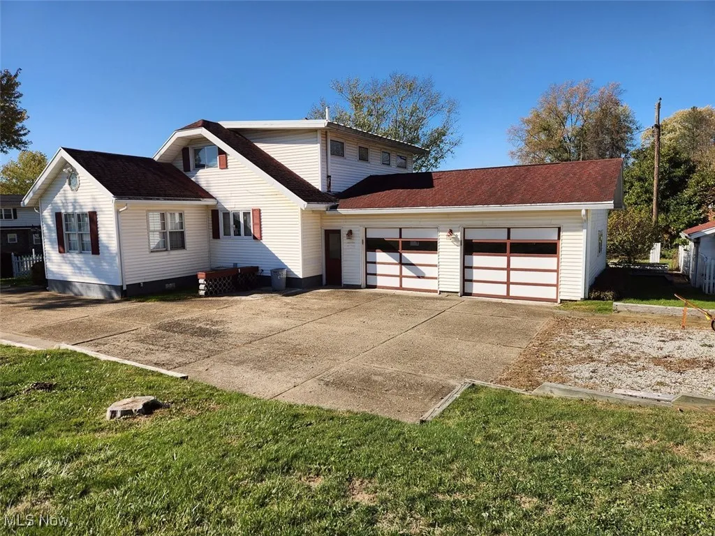 View of front of property with concrete driveway, an attached garage, and a front lawn