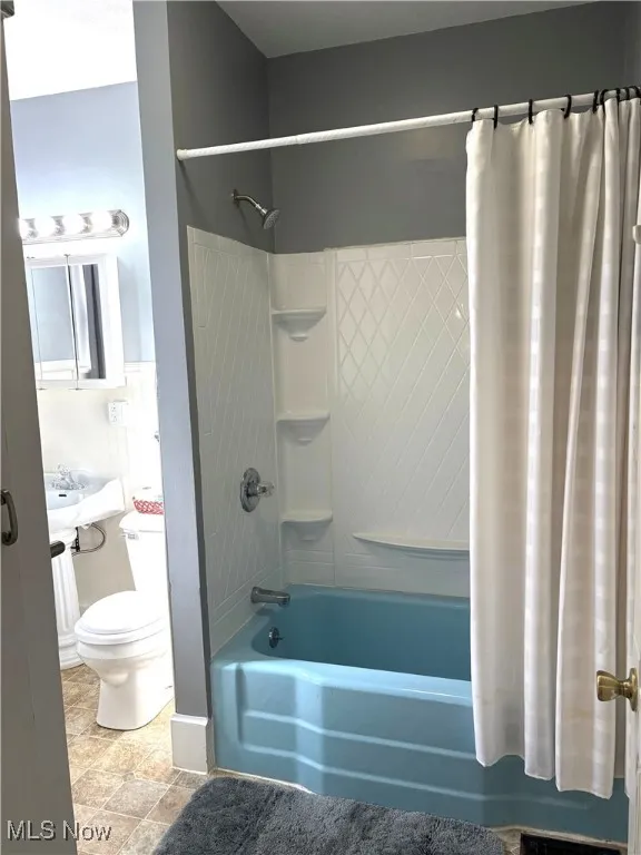 Bathroom featuring shower / bath combination with curtain and toilet