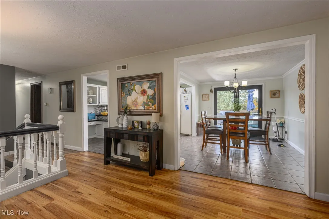 Dining area featuring light wood-style flooring, a chandelier, a textured ceiling, and ornamental molding